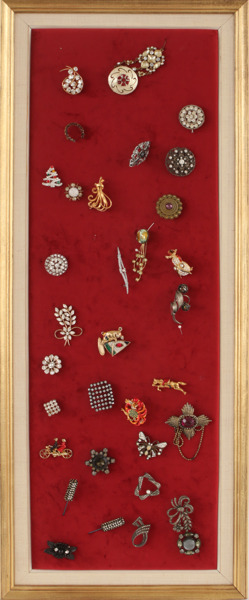 Tavla med broscher, bl.a. av silver